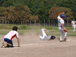 一塁にスライディングして戻るランナー