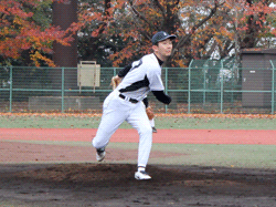 ネット裏のフェンス、くの字にぶら下がるマネージャー